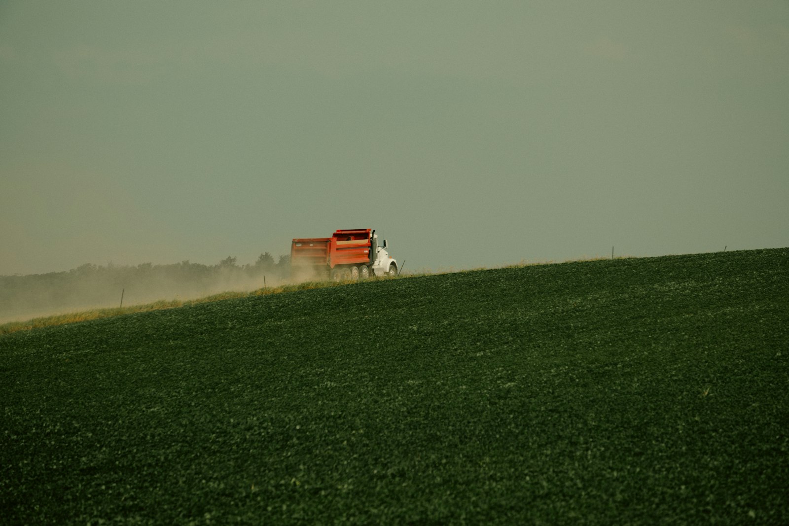 Dump truck hauling across a rural field ridge — Unsplash illustrative, not a tagged AIX job